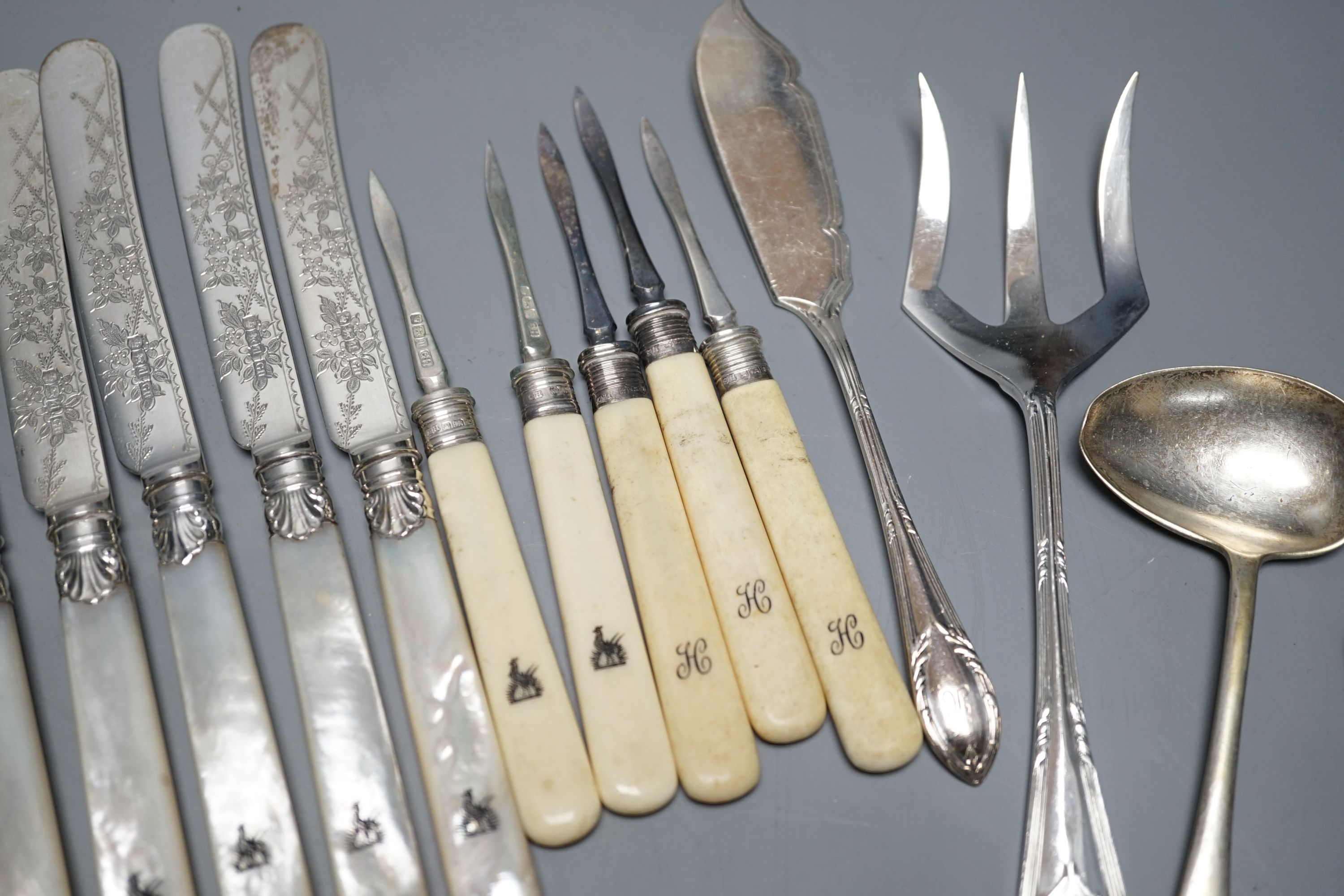 Six pairs of George V mother of pearl handled silver dessert eaters, George Howson, Sheffield, 1921, a pair of silver sugar tongs and assorted plated flatware.
